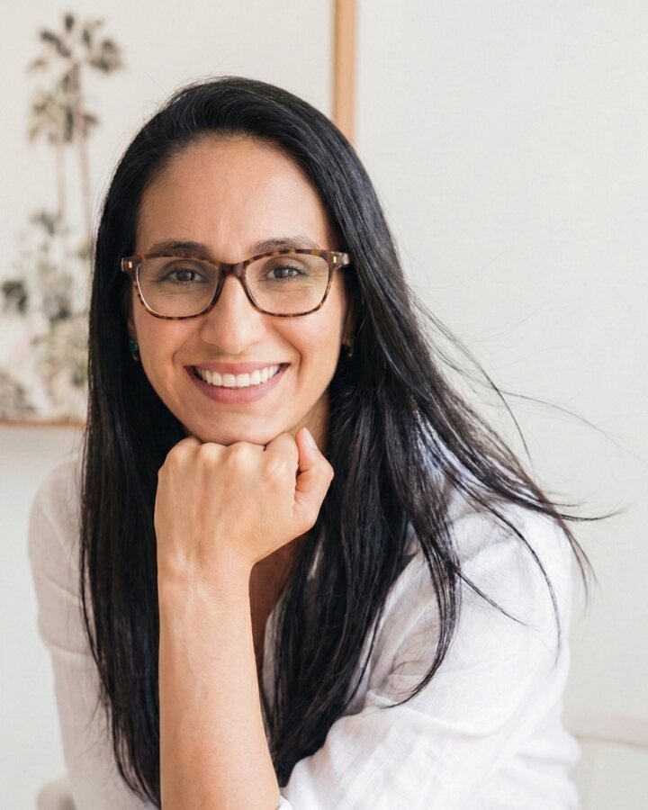 Prof. Dai Veloso sorrindo, sentada, com a mão no queixo